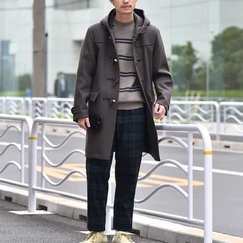 チャコールのダッフルコートにボーダーのニットとチェックのパンツを合わせた男性